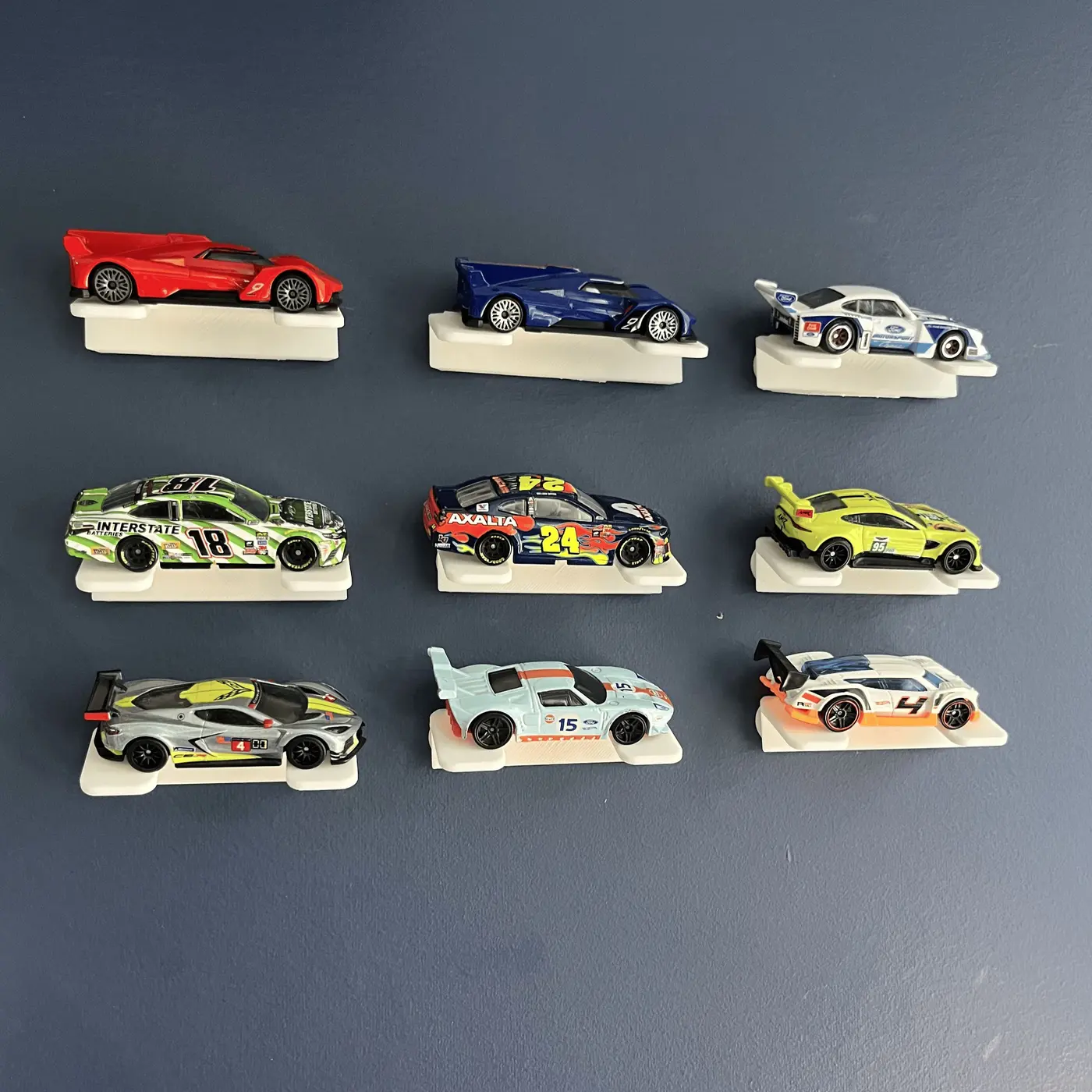Nine die-cast race cars arranged on individual white wall mounts