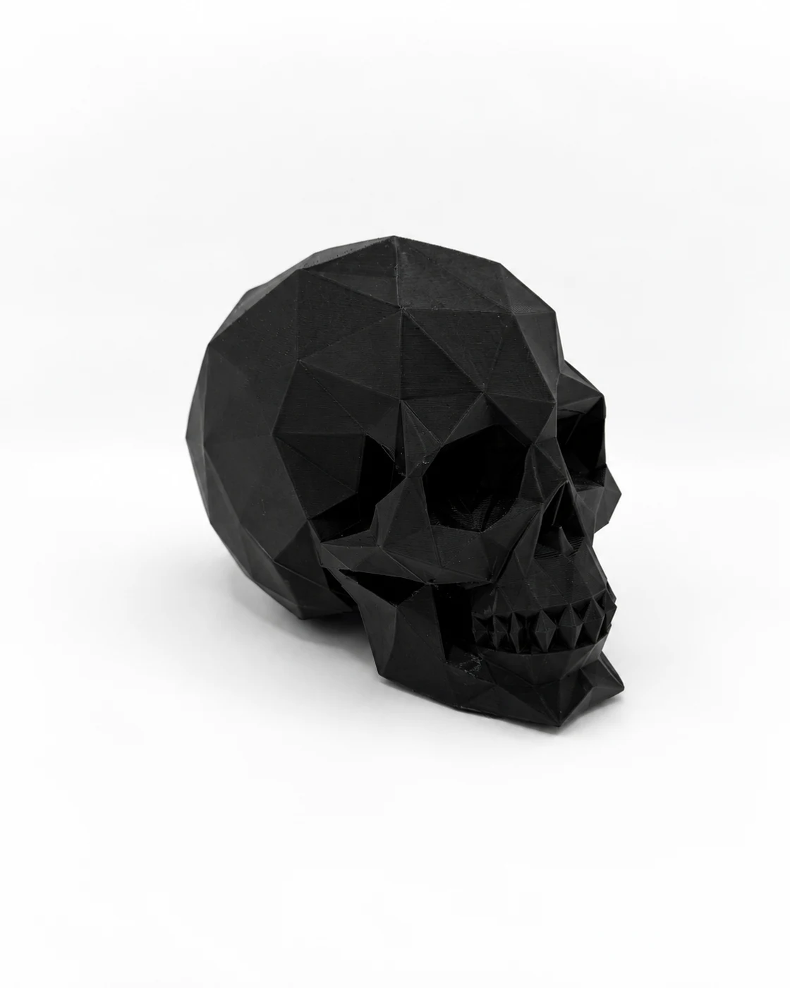 Black low-poly skull photographed at an angle on a white background